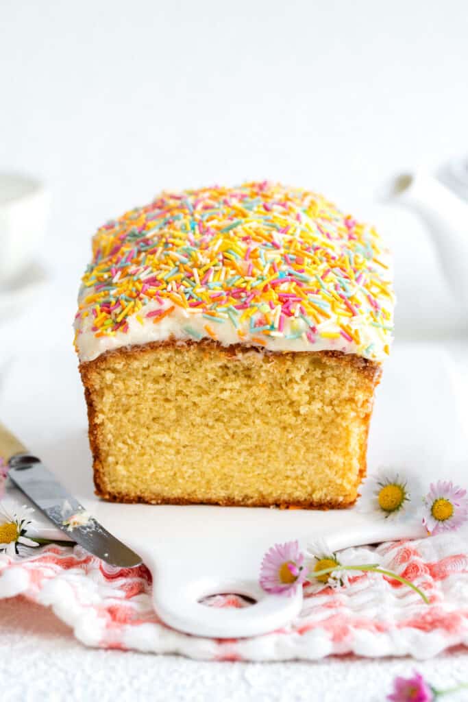 Sliced vanilla loaf cake topped with frosting and sprinkles