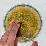 scooping out passion fruit pulp into a jar