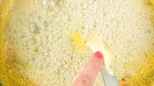 adding butter to boiling jam