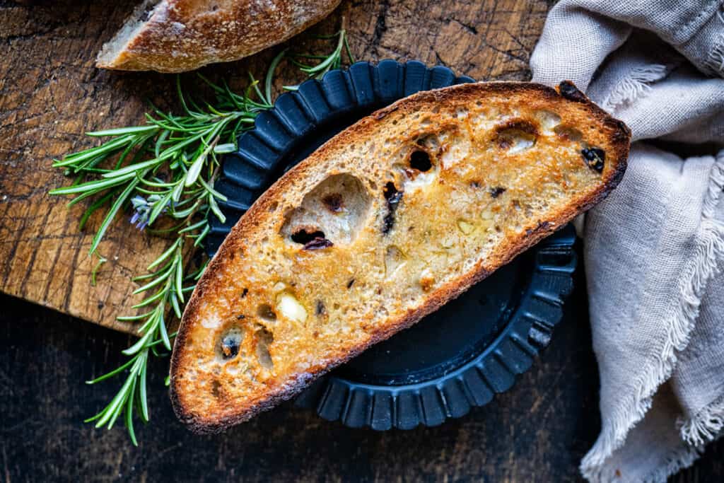 slice of toasted sourdough olive bread spread with butter