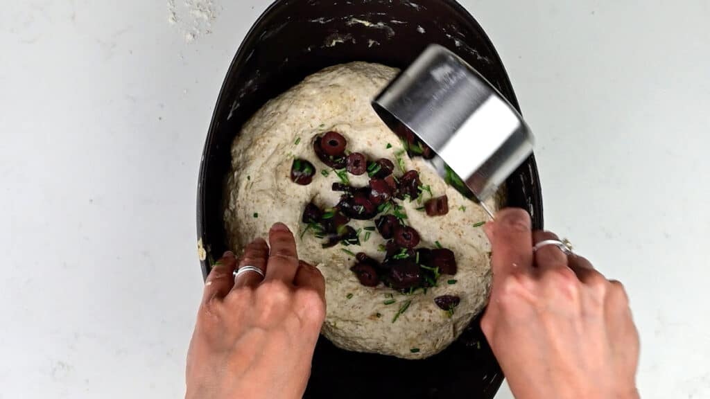 adding olives and rosemary to bread dough