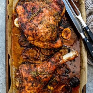 roasted turkey legs on a tray with carving set on the side