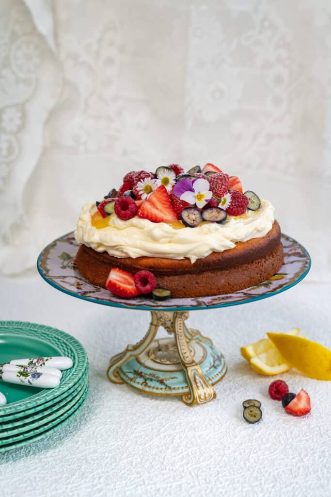 Yogurt Cake topped with cream and berries on a cake stand