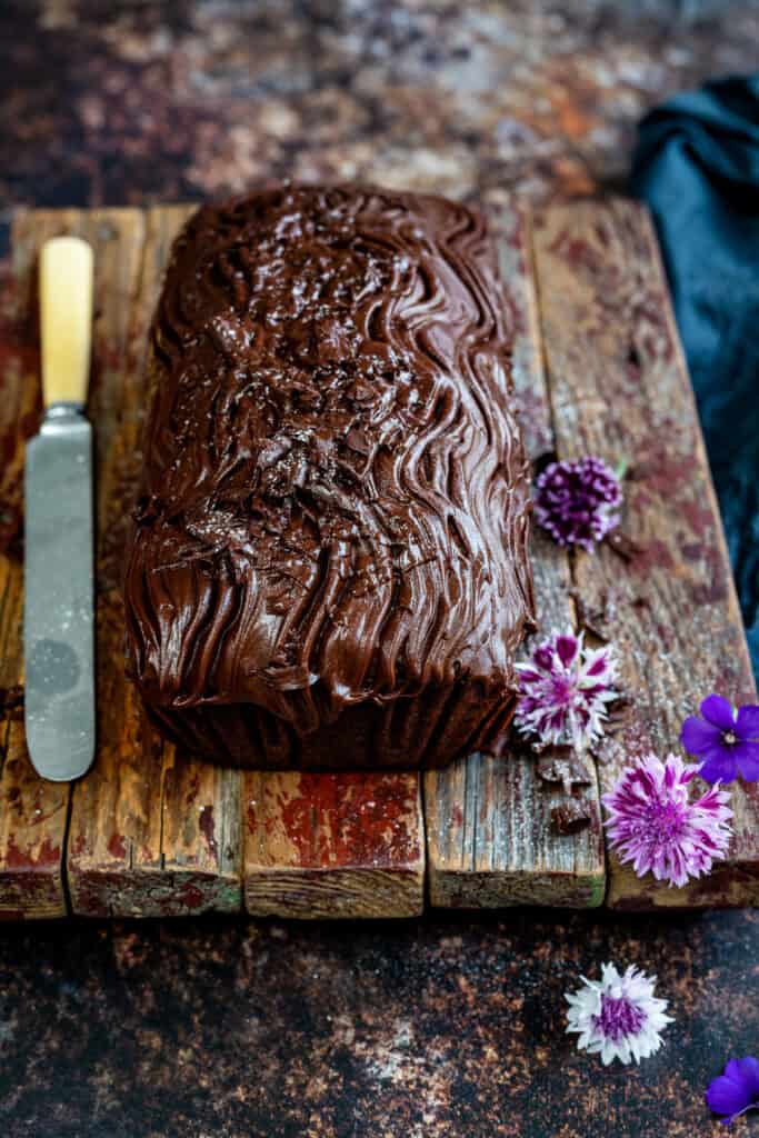 Chocolate loaf cake topped with chocolate glaze on a wooden board