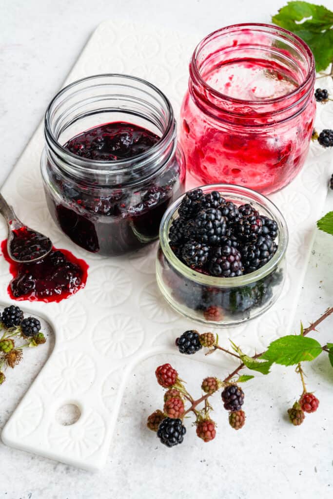 Jar of homemade black berry jam with small jar of blackberries on the dide