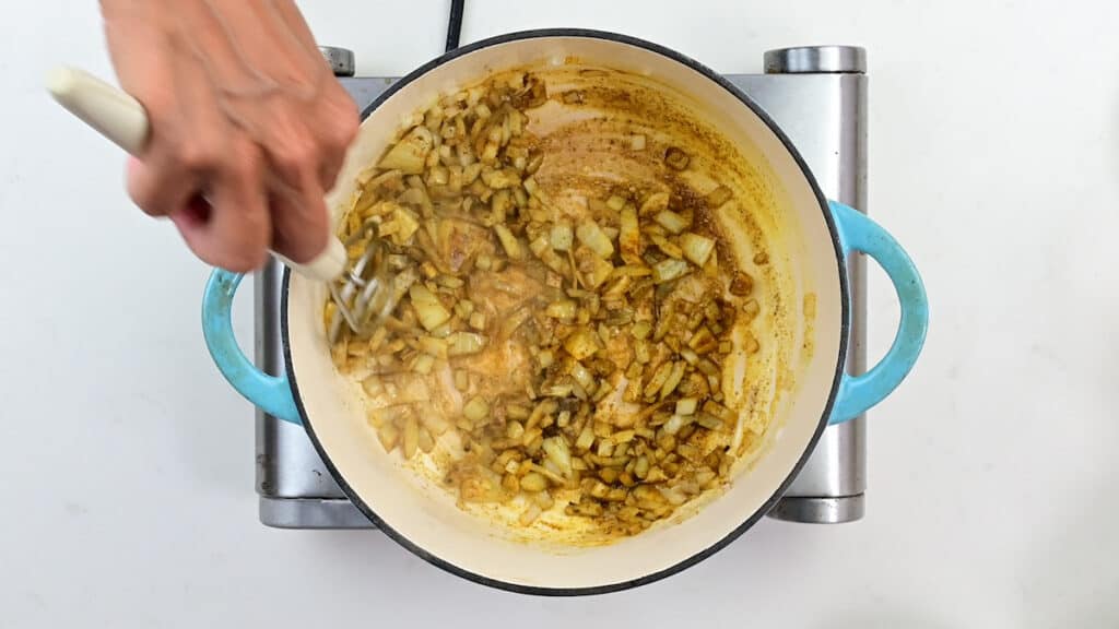 cooking diced onions with spices in a large pot