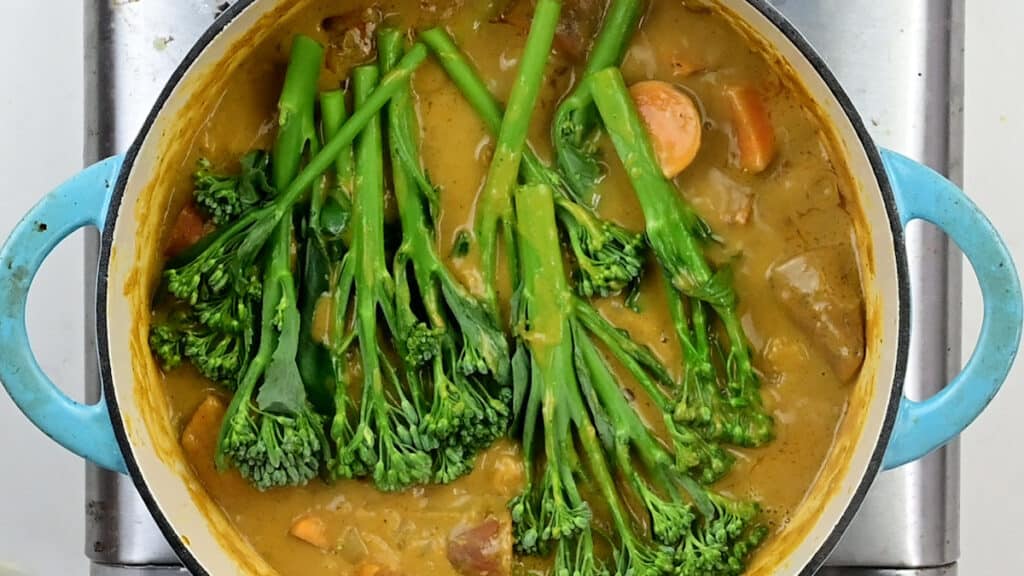 Broccolini added to pot of sweet potato curry