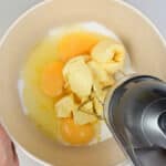 Beating sugar, eggs, butter and zest together in a bowl using an electric hand mixer