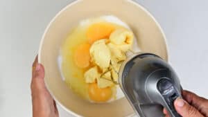 Beating sugar, eggs, butter and zest together in a bowl using an electric hand mixer