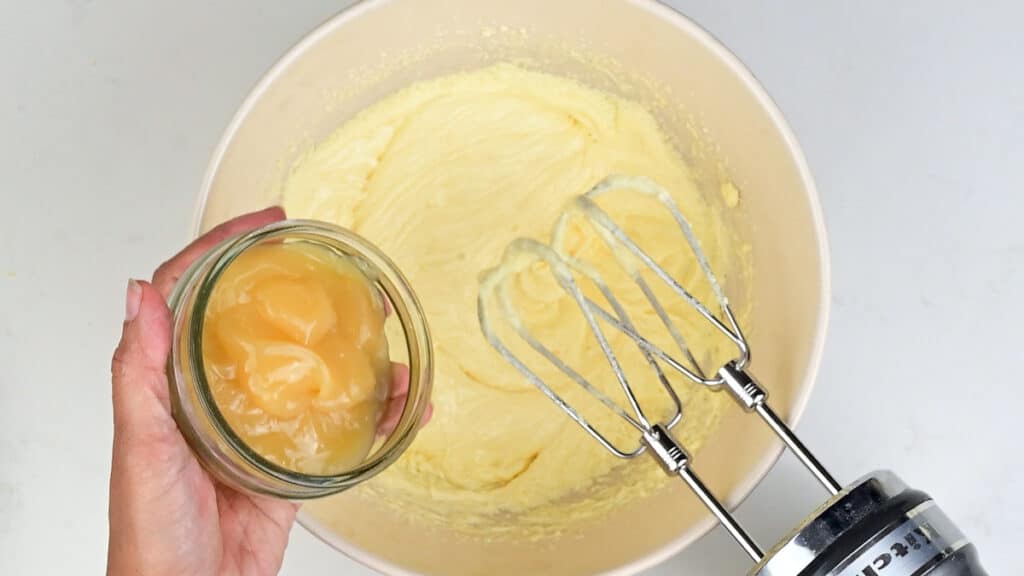 Adding lemon curd to mixing bowl of cake batter