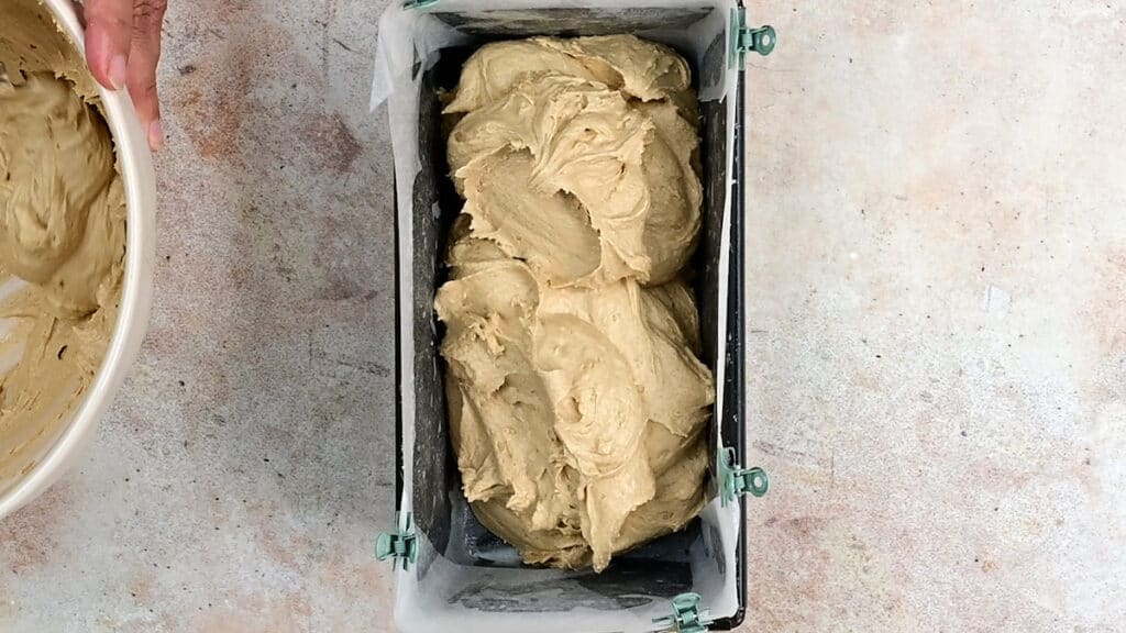spooning cake batter into a lined loaf tin