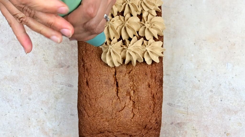 Piping Biscoff buttercream over cookie butter loaf