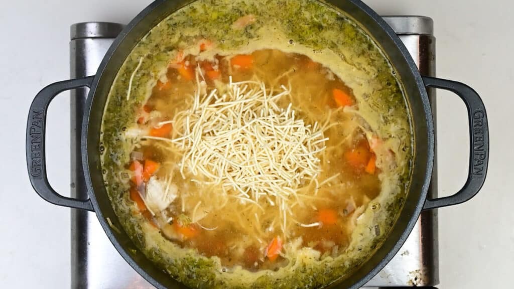 adding vermicelli noodles to pot of chicken soup