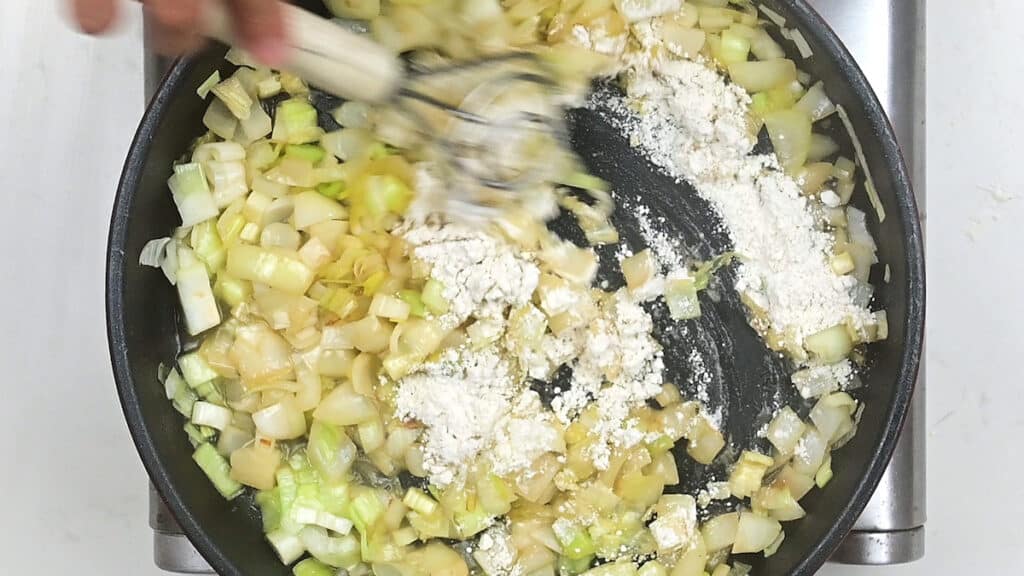 Stirring flour into pan with leeks and onions