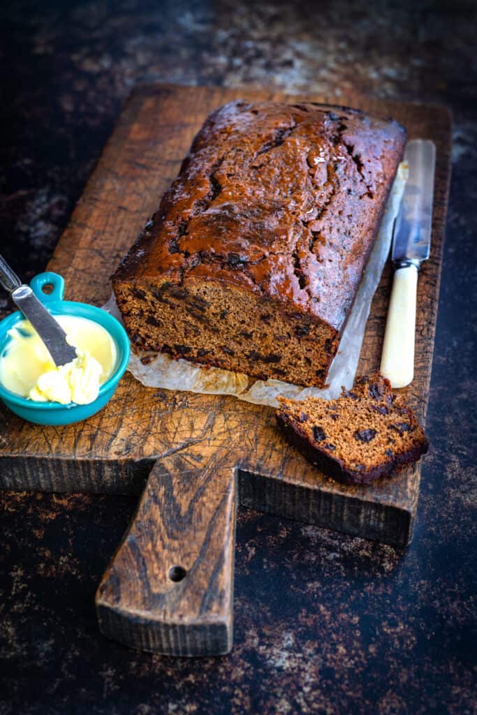 Malt loaf with butter on the side on a rustic cutting board