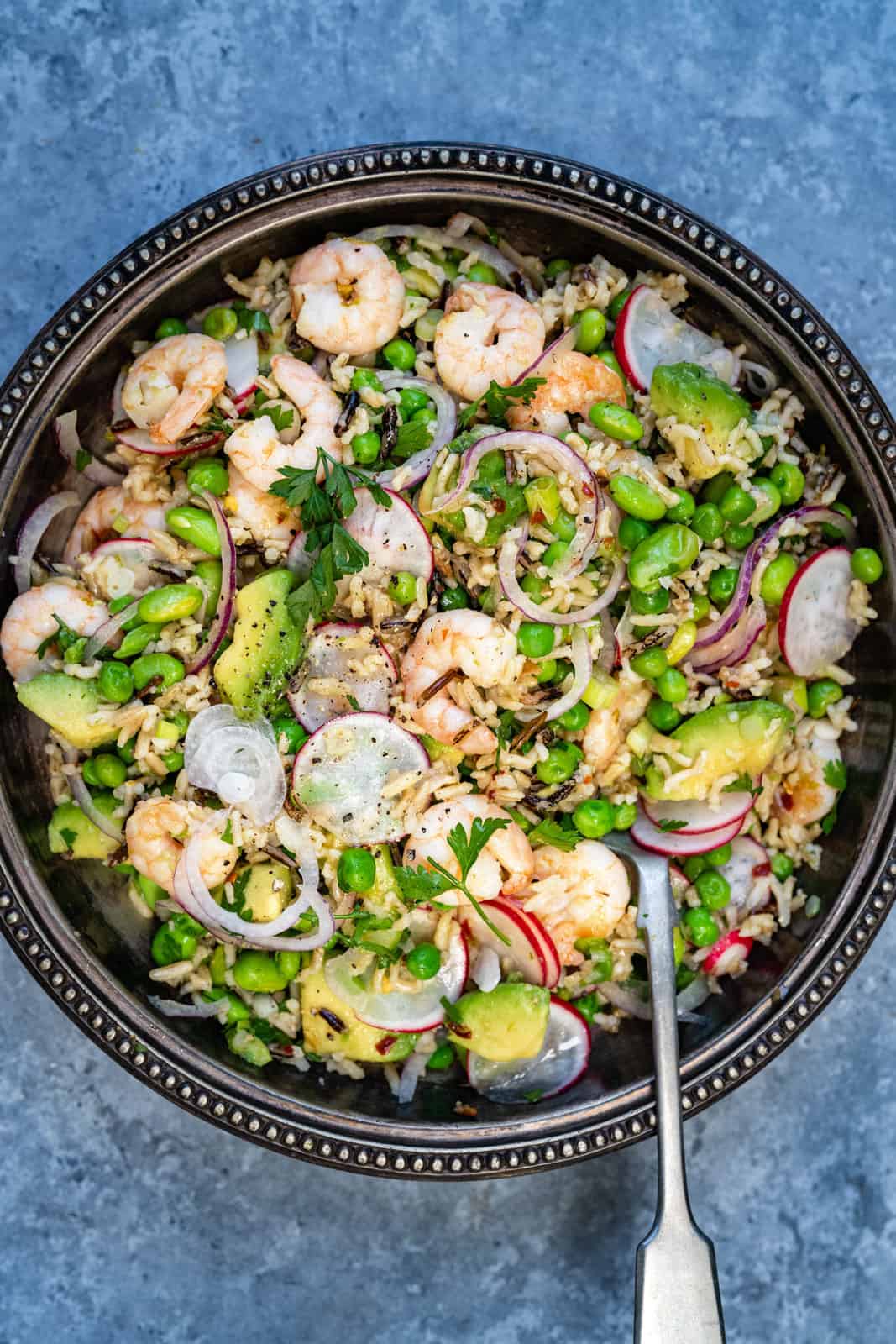Close up on a bowl of prawn salad with avocado, peas and rice