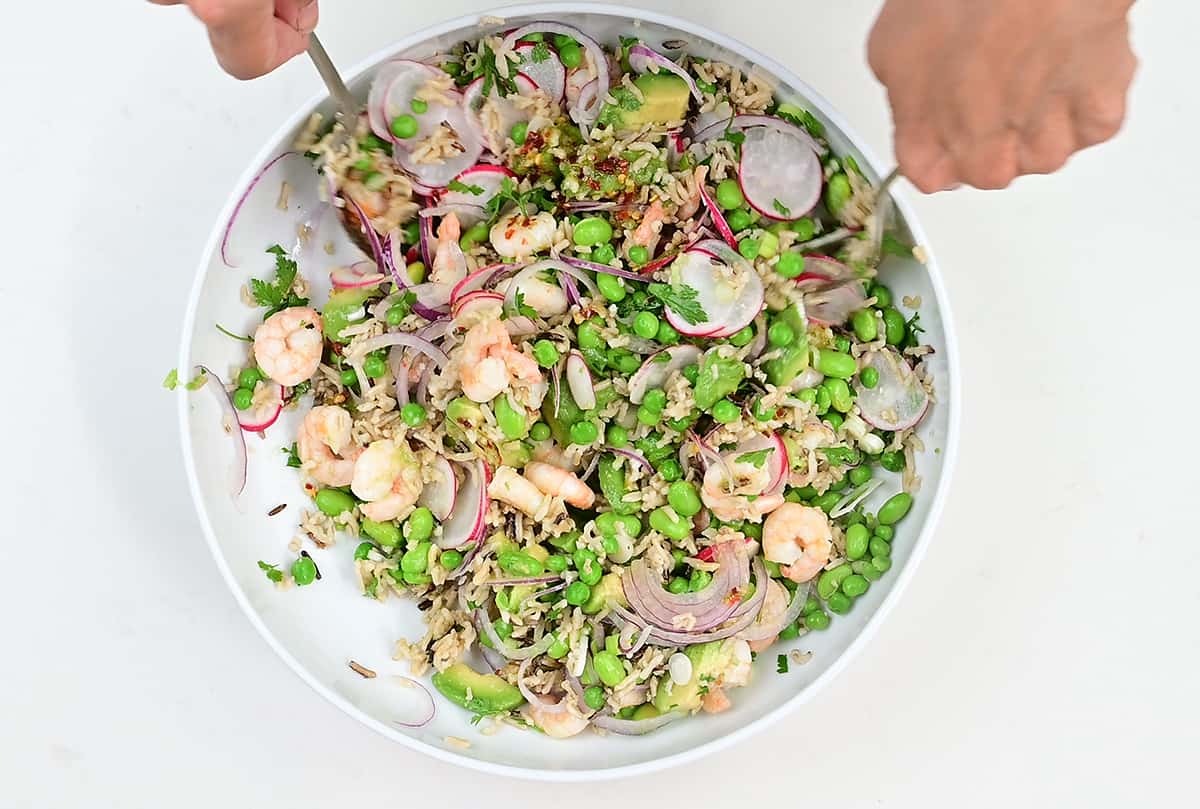 Tossing prawn salad ingredients in a large white bowl