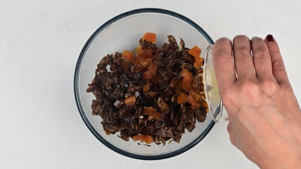 adding brandy to bowl with chopped dates and dried apricots