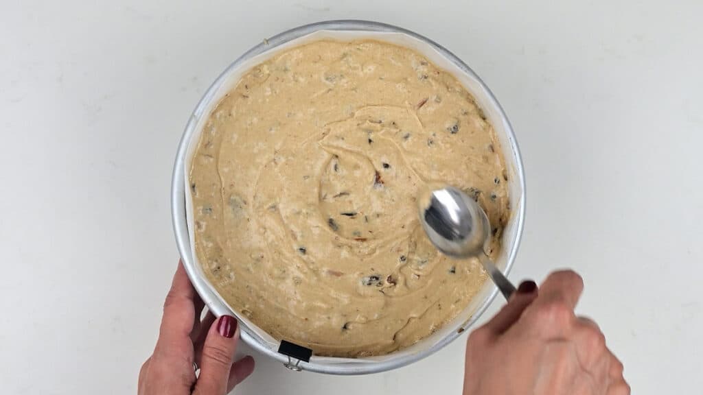 levelling Christmas cake batter in a cake tin with a spoon