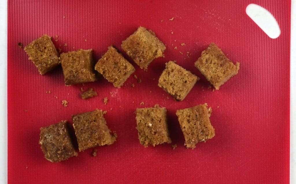 cubes of ginger cake on a red cutting board