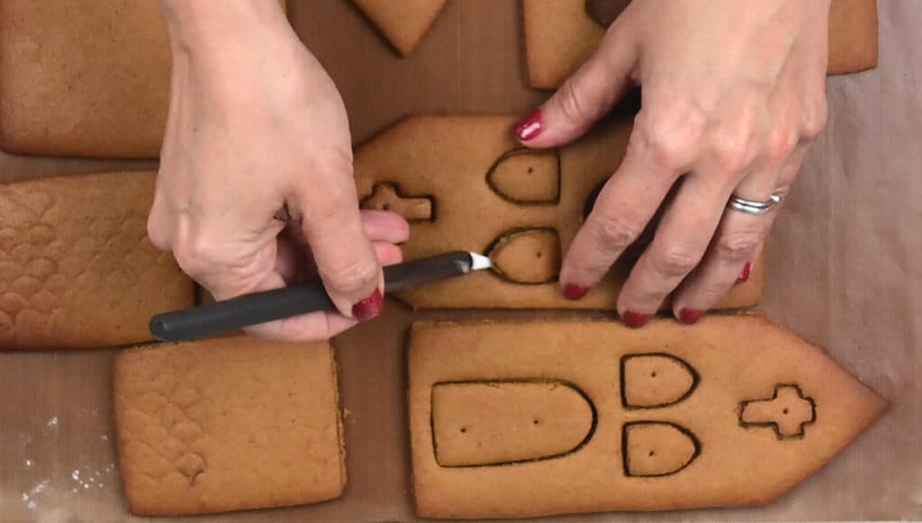Removing the windows from baked gingerbread house panels using a knife