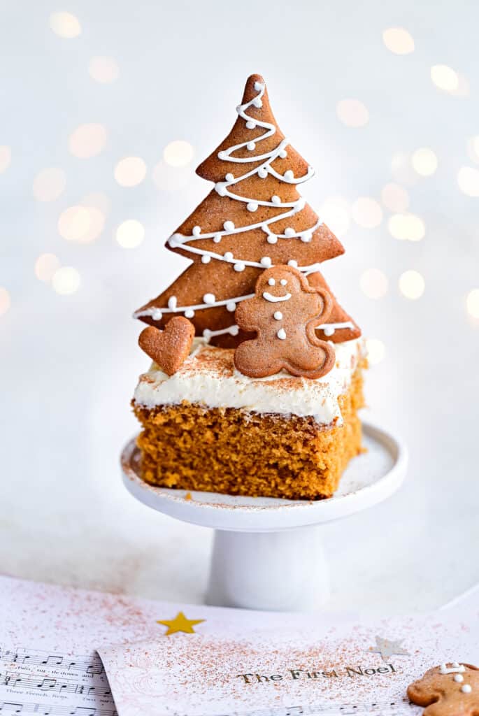 slice of Gingerbread traybake with mascarpone frosting topeed with gingebread christmas tree cookies