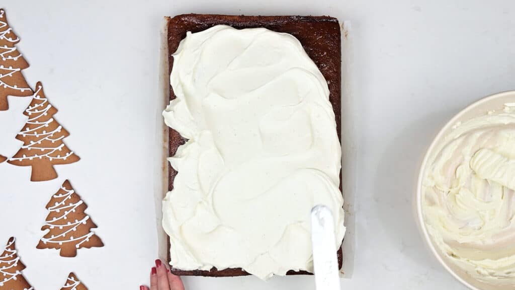 spreading mascarpone frosting over gingebread sheet cake