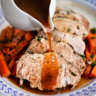 Sliced slow cooker pork roast on a platter drizzled with gravy