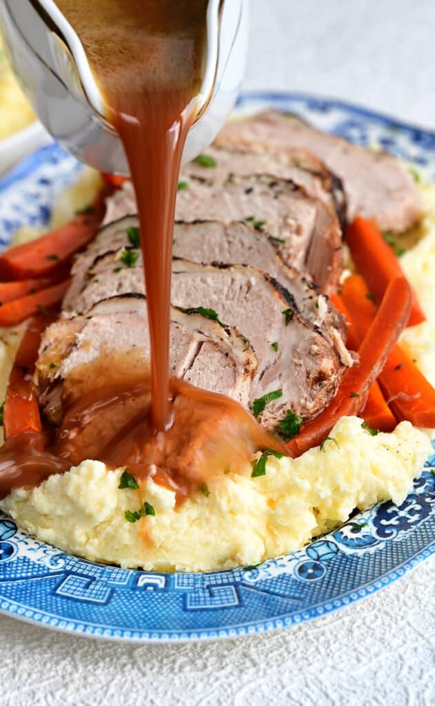 Pork roast served over mashed potatoes with carrots and gravy