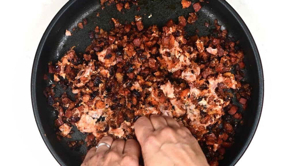 adding sausage meat to stuffing in a skillet