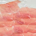 overlapping slices of prosciutto on cling film