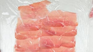 overlapping slices of prosciutto on cling film