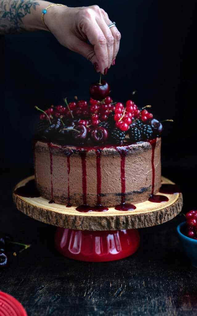 Vegan chocolate cake decorated with blackberries, cherries and redcurrants