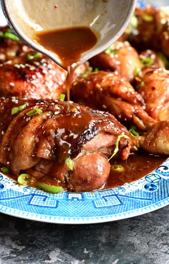 Pouring sauce over sticky chicken thighs