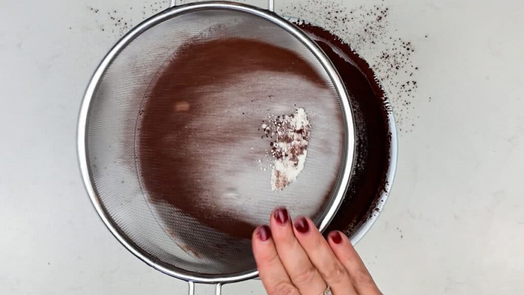 sifting flour and cocoa powder into brownie batter