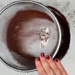 sifting flour and cocoa powder into brownie batter