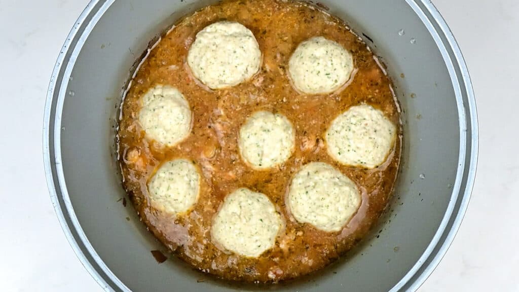 Placing dumplings over chicken stew in a crockpot