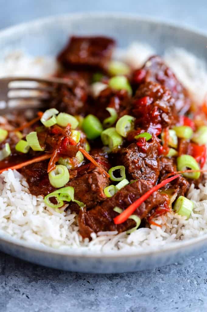Slow Cooker Mongolian Beef served with rice and sliced green onions