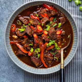 Bowl of Mongolian Beef with green onion and red pepper garnish