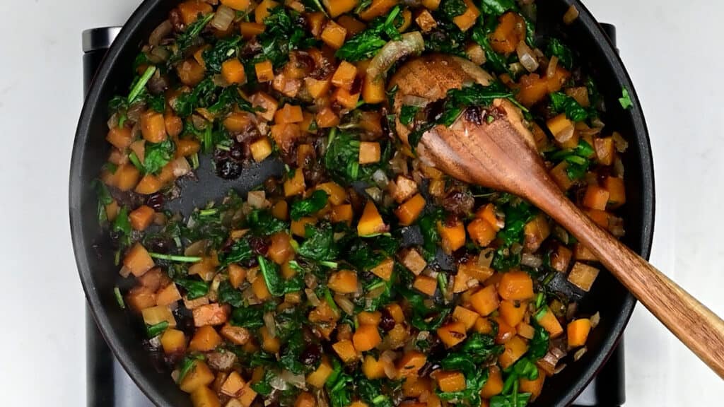Cooking diced squash and spinach in a skillet