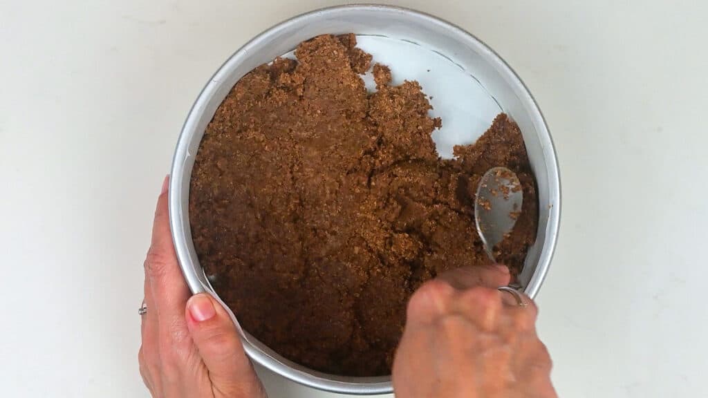 pressing cookie crumb crust into cake tin