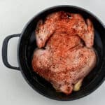 Whole seasoned chicken placed in a Dutch oven breast side down
