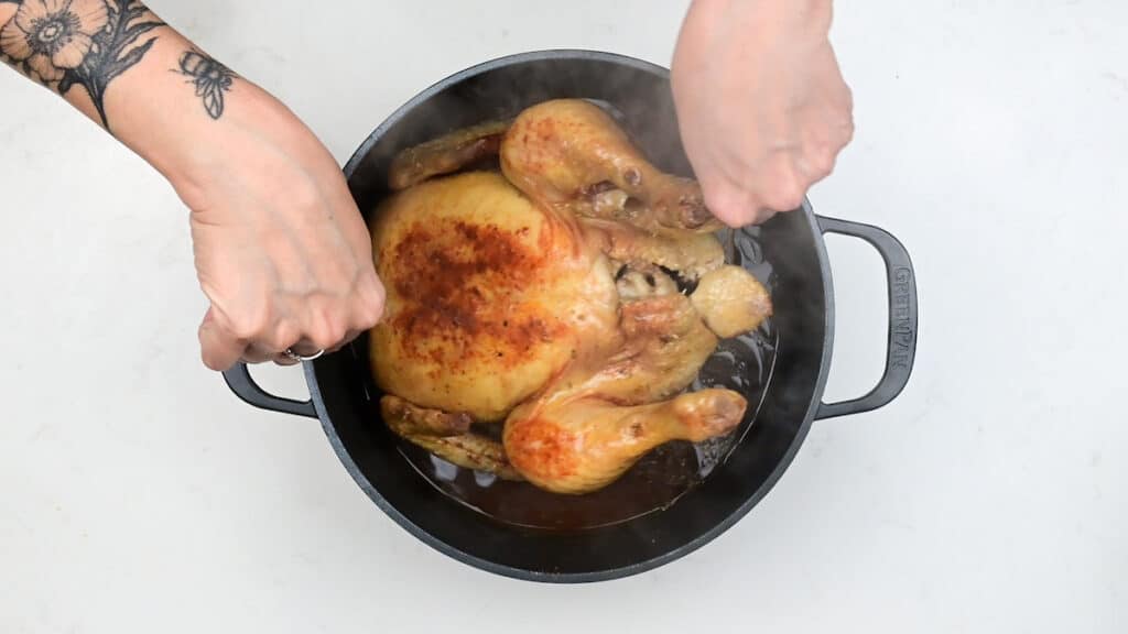 Partially cooked pot roast chicken in a Dutch oven