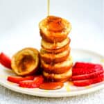Stack of mini pancakes being drizzled with maple syrup