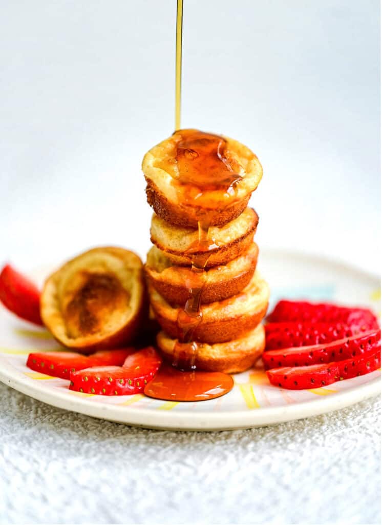Stack of mini pancakes being drizzled with maple syrup