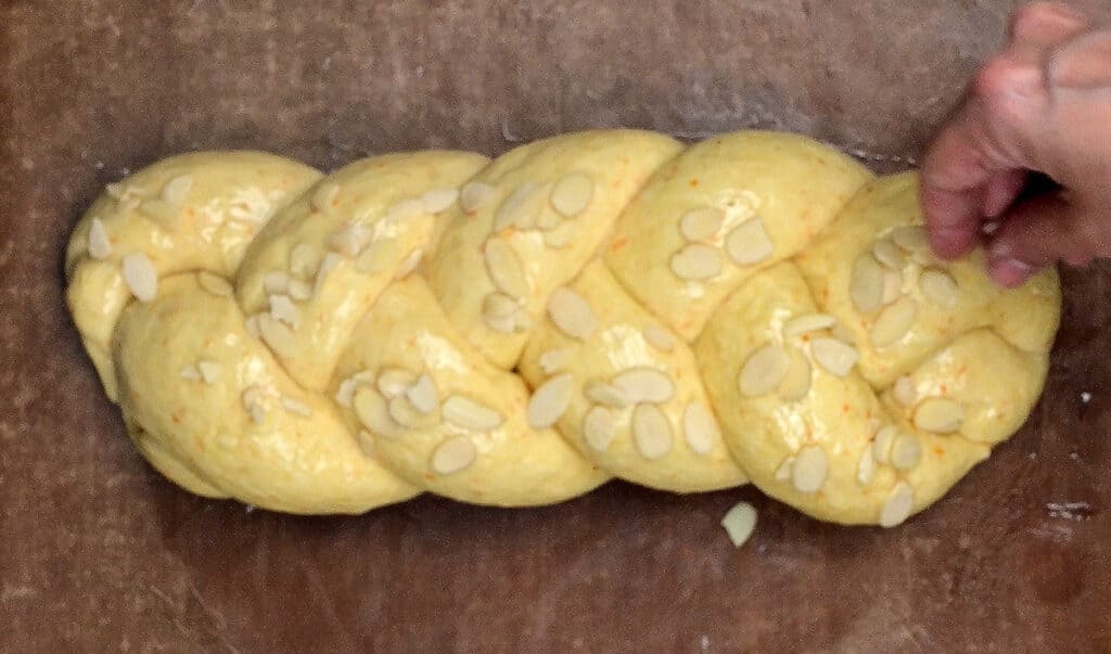 Topping braided tsoureki dough with flaked almonds