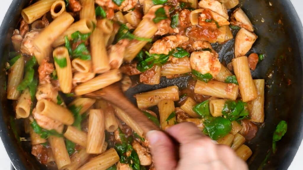stirring spinach into pasta dish