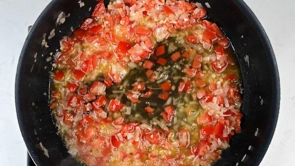 tomatoes cooking with wine and shallots in a pan