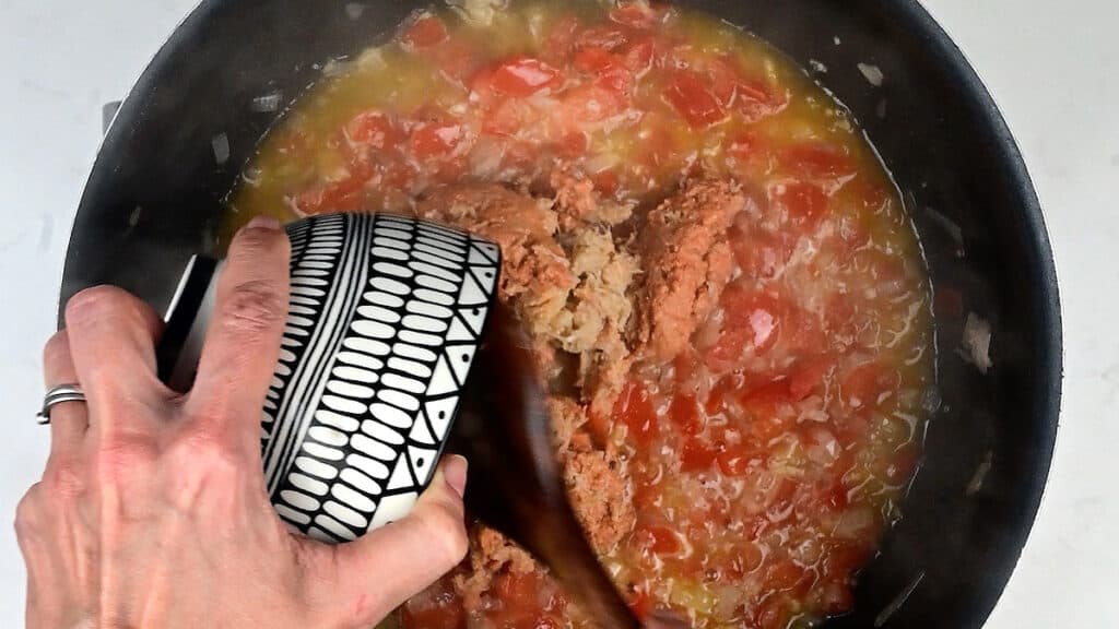 adding crab meat to tomato sauce in a pan
