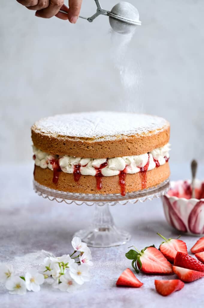 Dusting Victoria sponge with icing sugar